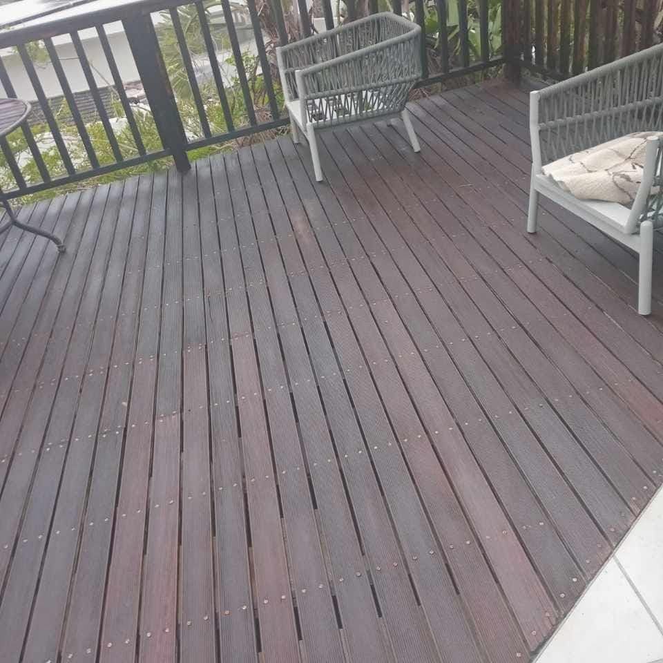 Finished dark timber deck with outdoor chairs and a garden railing