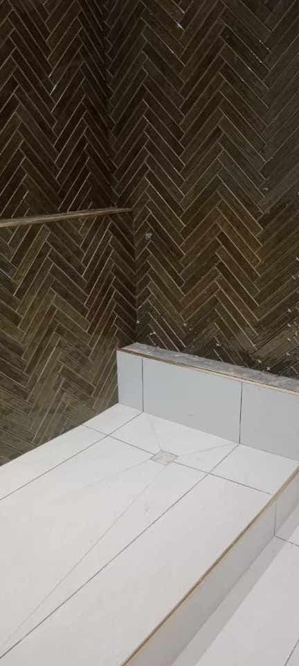 Herringbone wall tiles above a white tiled shower floor