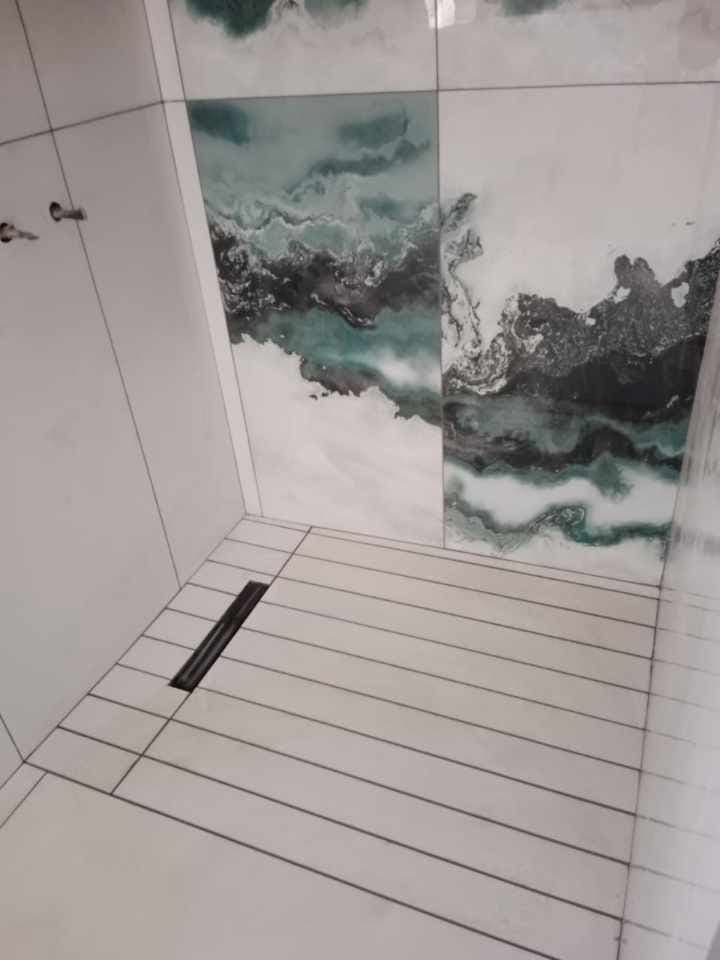 Walk-in shower with teal feature tiles and a linear drain