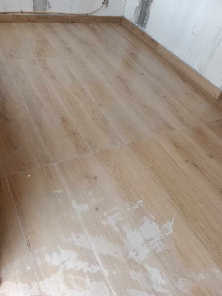 Room with wood-look flooring and walls being skimmed for paint