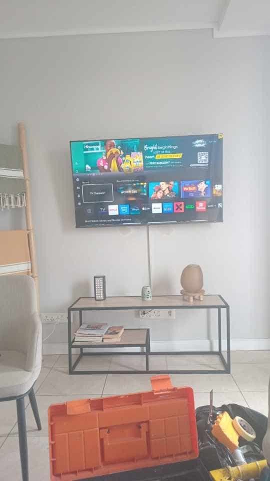 Flat-screen TV mounted on a grey wall with tidy cable trunking